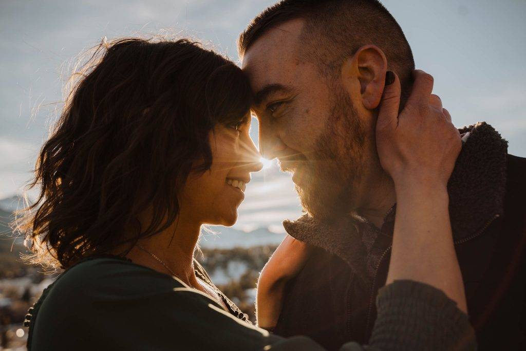 a bride and groom touching foreheads with the sun peeking through in estes park, Colorado