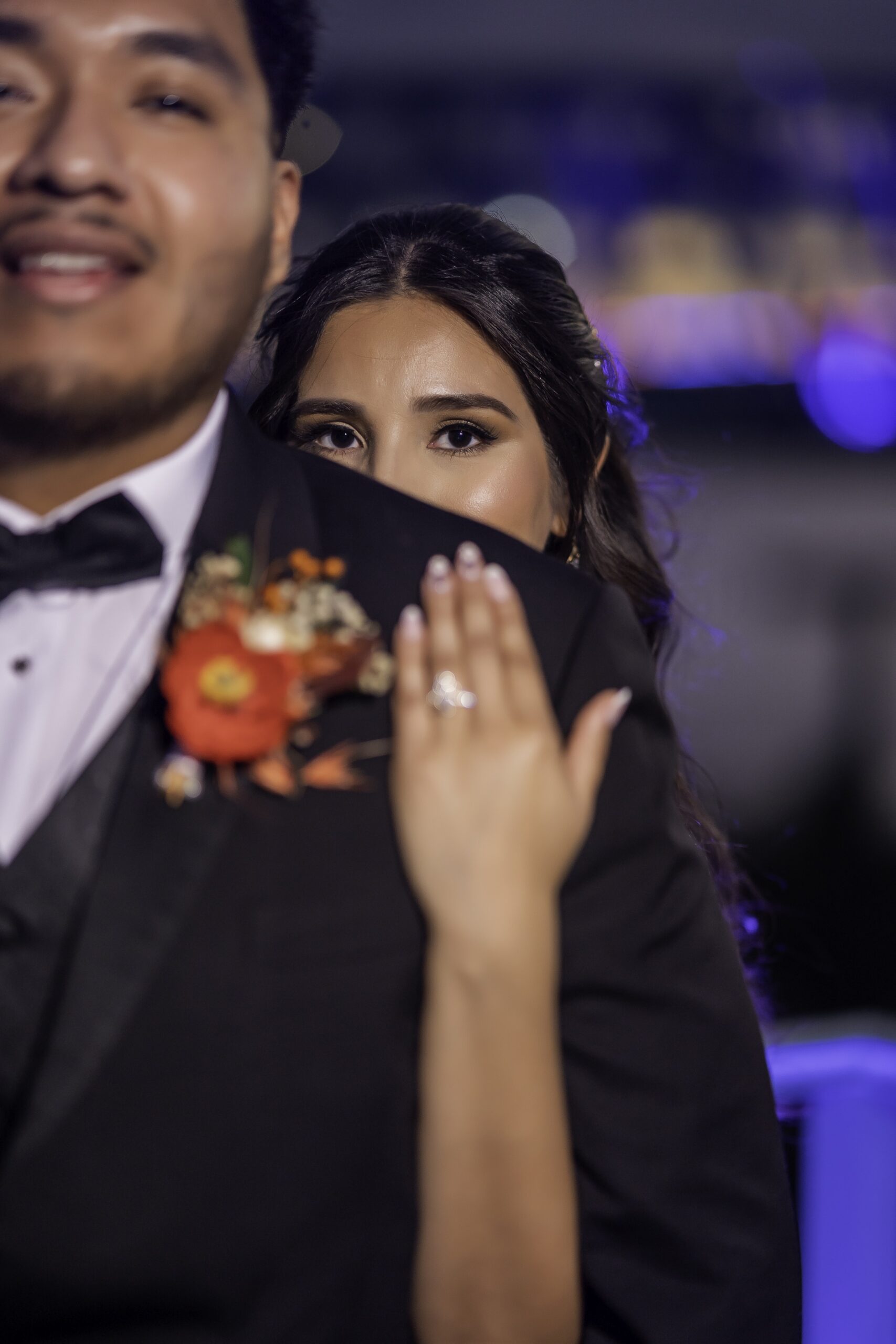 A bride posing behind a groom's shoulder