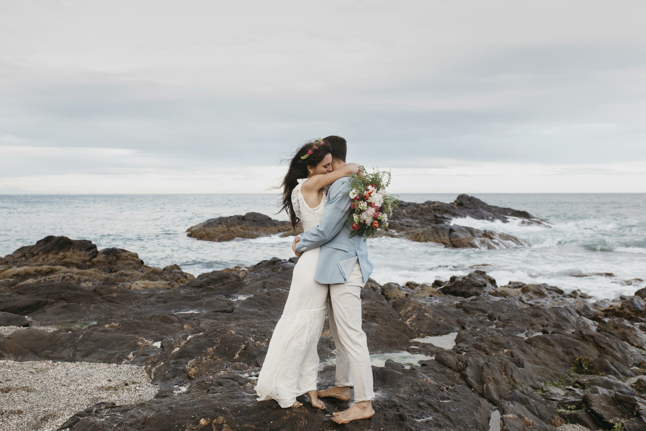 Miami wedding photographers photographing a couple hugging one another on the rocks of the ocean