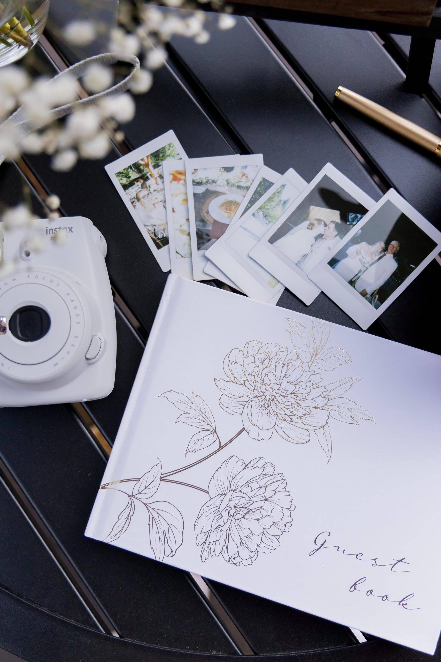 photographs on a wedding table with flowers and guest book.