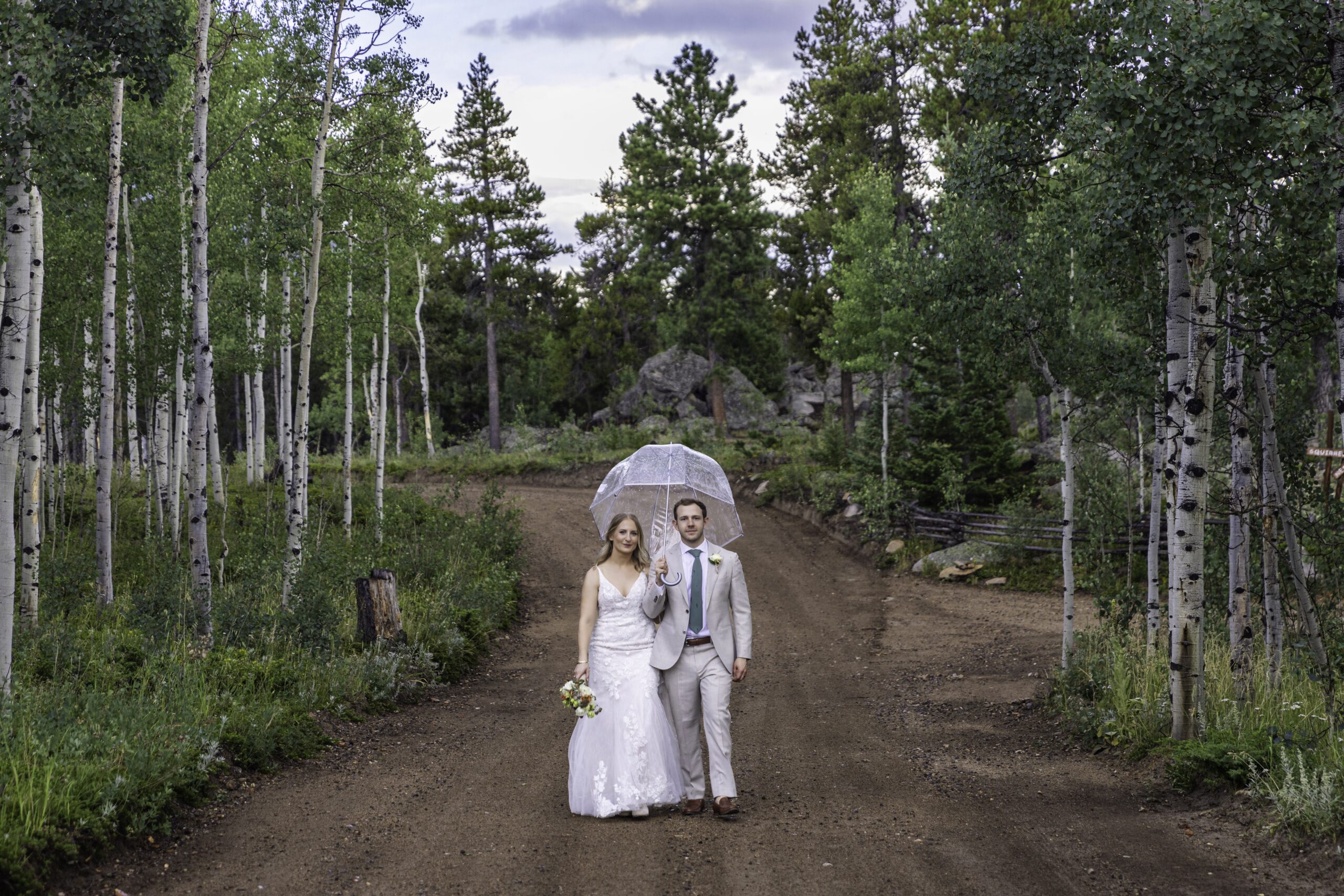 A bride in groom in an Aspen forest in Colorado stand under an umbrella.