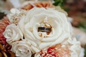 bridal. bouqet of flowers with wedding rings places on top.