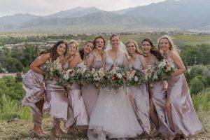 bridal party with flower bouquets and mountains in the background.