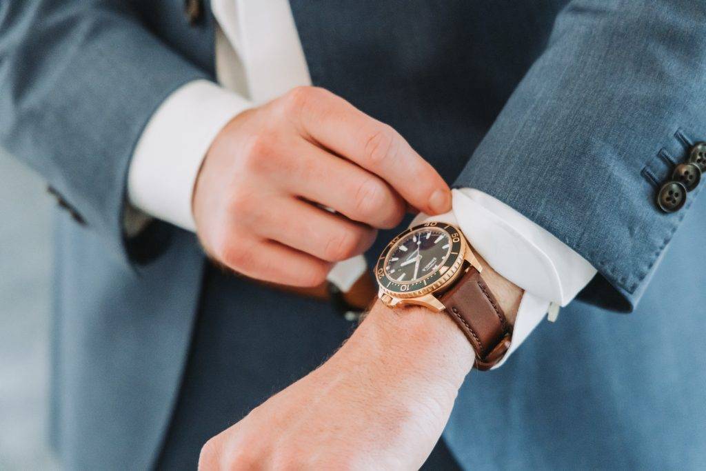 a close up shot of a groom in a blue suit adjusting his cuffs.