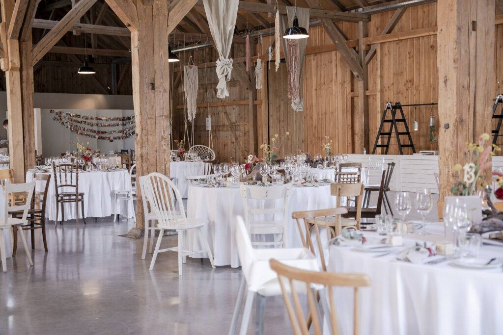 A beautifully decorated wooden wedding area with white covered tables