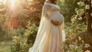 A maternity gown hanging on a blooming flower bush in a lush woodland setting.