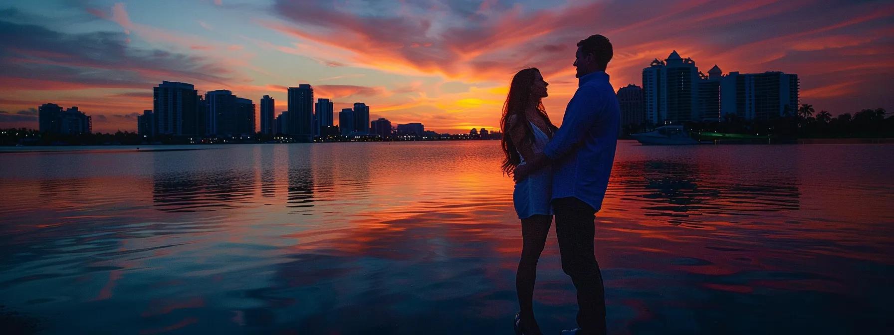 vibrant miami skyline reflecting in the calm waters as a happy couple poses for their engagement photos at sunset.