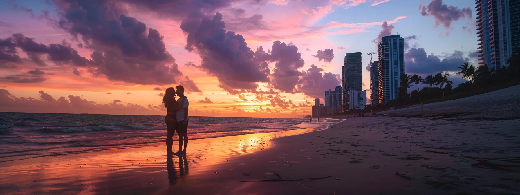 a couple embracing under a pastel-colored sunset on the sandy shores of miami beach.